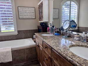 Bathroom featuring plenty of natural light, double vanity, and a bath