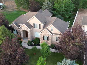 View of front of property featuring stone siding, stucco siding, a shingled roof, and a front yard