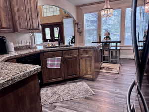 Kitchen with a peninsula, dark wood-style floors, arched walkways, and a chandelier