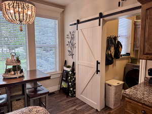 Dining area featuring a barn door, dark wood-style floors, and a chandelier