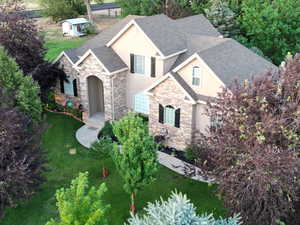 French country inspired facade featuring stone siding, stucco siding, a shingled roof, and a front yard
