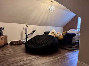 Detailed view of wood finished floors, a textured ceiling, and a chandelier