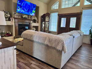 Living room featuring dark wood finished floors, vaulted ceiling, and a glass covered fireplace