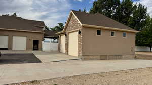 View of side of home with stone siding, stucco siding, an outbuilding, and a detached garage