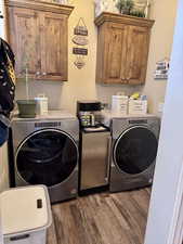 Laundry area featuring cabinet space, separate washer and dryer, and wood finished floors