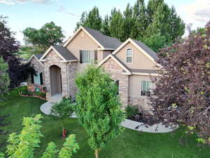 View of front of home with stucco siding, stone siding, and a front lawn
