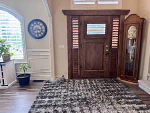 Foyer featuring wood finished floors, plenty of natural light, wainscoting, and a decorative wall