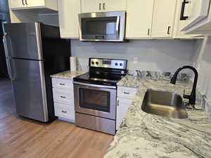 Kitchen featuring stainless steel appliances, light wood finished floors, and white cabinetry