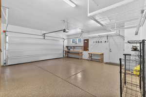 Garage featuring epoxy floors, workbench and upper hanging storage racks
