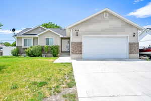 Ranch-style house with brick siding, driveway, a front lawn, and a garage