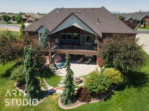 Rear view of house featuring a shingled roof, a patio area, an outdoor fire pit, stairway, and a lawn