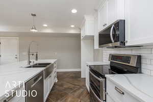 Kitchen with appliances with stainless steel finishes, dark stone finish floors, recessed lighting, white cabinetry, and light stone counters