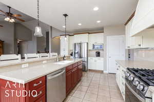 Kitchen featuring appliances with stainless steel finishes, ceiling fan, premium range hood, light tile patterned floors, and a kitchen island with sink