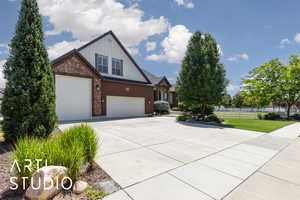 View of front facade featuring board and batten siding, driveway, brick siding, and a garage