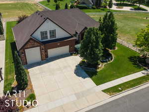 View of front of property with a garage, concrete driveway, roof with shingles, and stone siding