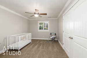Bedroom featuring carpet floors, ornamental molding, a crib, and ceiling fan