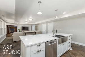 Kitchen featuring dishwasher, open floor plan, white cabinets, pendant lighting, and a kitchen island with sink