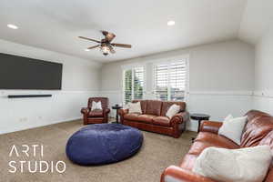 Carpeted living area with lofted ceiling, a ceiling fan, wainscoting, and recessed lighting