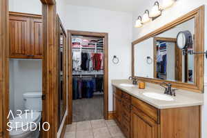 Full bath featuring double vanity, tile patterned floors, and a walk in closet