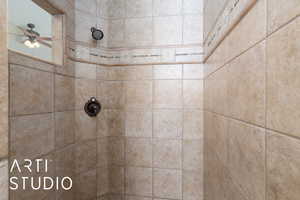 Full bath featuring a tile shower and a ceiling fan