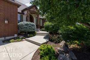 View of exterior entry featuring stone siding, a shingled roof, and brick siding
