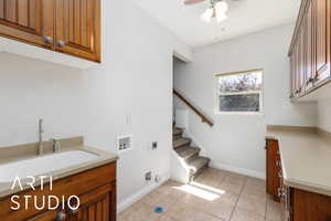 Washroom with hookup for an electric dryer, cabinet space, washer hookup, ceiling fan, and light tile patterned flooring