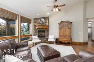 Living area with vaulted ceiling, a ceiling fan, hardwood / wood-style floors, and a fireplace