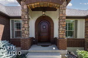 Property entrance with a shingled roof, brick siding, and stone siding