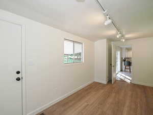 Unfurnished room featuring a textured ceiling, track lighting, and wood finished floors
