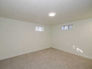 Basement featuring light colored carpet and a textured ceiling