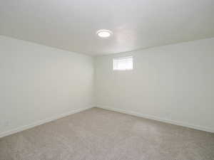 Empty room featuring light colored carpet and baseboards
