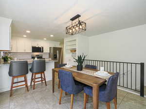 Dining area with a textured ceiling, recessed lighting, a chandelier, and light tile patterned floors
