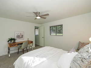 Bedroom with carpet flooring, ceiling fan, and a desk