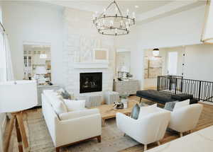 Living area with a high ceiling, a chandelier, a fireplace, and wood finished floors