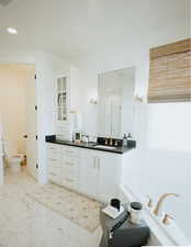 Full bathroom featuring vanity, a garden tub, recessed lighting, and marble look tile flooring