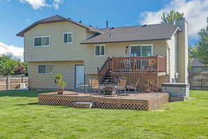 Rear view of property featuring a deck, a chimney, and a shingled roof