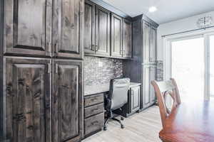 Office with light wood-style flooring and built in desk