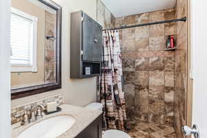 Bathroom with vanity, tiled shower, and decorative backsplash