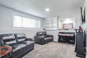 Carpeted living room featuring a textured ceiling, and built in shelves