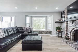 Living area featuring a brick fireplace, wood finished floors, recessed lighting, and a textured ceiling