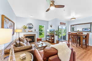 Living area with a fireplace, light wood finished floors, and a ceiling fan