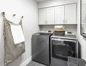 Washroom with washing machine and dryer, cabinet space, and light tile patterned floors