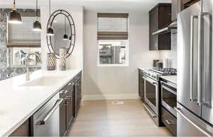 Kitchen with premium appliances, backsplash, dark brown cabinets, and light countertops