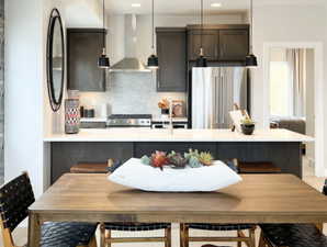 Kitchen with freestanding refrigerator, wall chimney exhaust hood, tasteful backsplash, light countertops, and recessed lighting