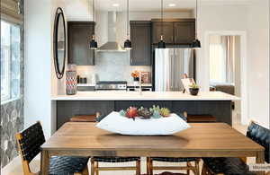 Kitchen with exhaust hood, freestanding refrigerator, range, tasteful backsplash, and light countertops