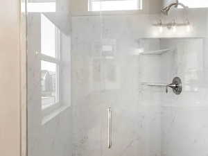 Full bath with a marble finish shower