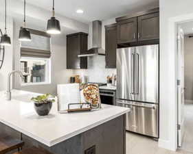 Kitchen featuring stainless steel appliances, wall chimney range hood, tasteful backsplash, dark brown cabinetry, and recessed lighting
