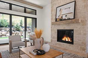 Living area featuring wood finished floors, a fireplace, and beamed ceiling