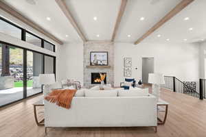 Living room with a stone fireplace, recessed lighting, beamed ceiling, and light wood-style floors