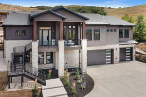 View of front of house featuring stone siding, a garage, a standing seam roof, and driveway
